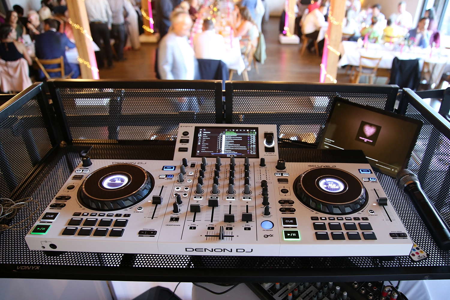 Graues Denon DJ Pult von DJ Jürgen steht auf schwarzem Gitter. Im Hintergrund die Hochzeitsgesellschaft.